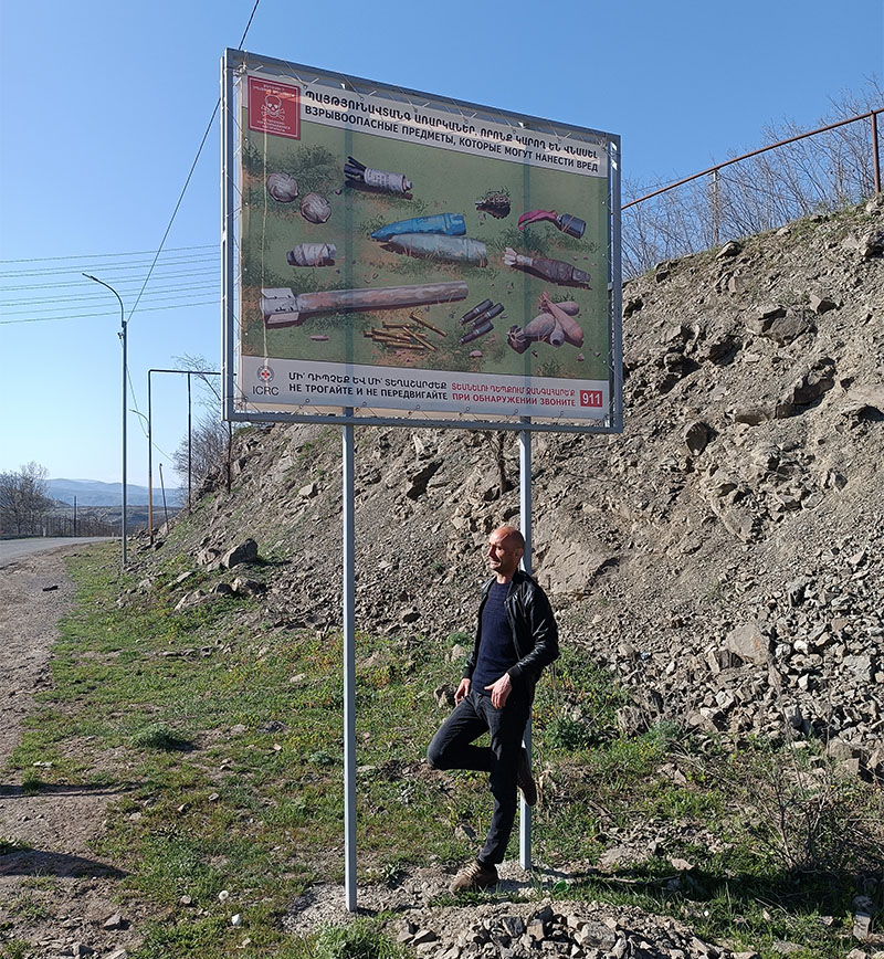 Blogger and journalist Marut Vanyan, next to a Red Cross sign warning of unexploded munitions, remnants of the many wars that have taken place in the region (Photo: Yaron Weiss).